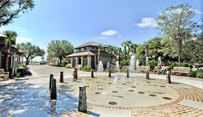 Ein Innenhof mit einem Brunnen, Palmen und einem Gebäude mit Ziegeldach.