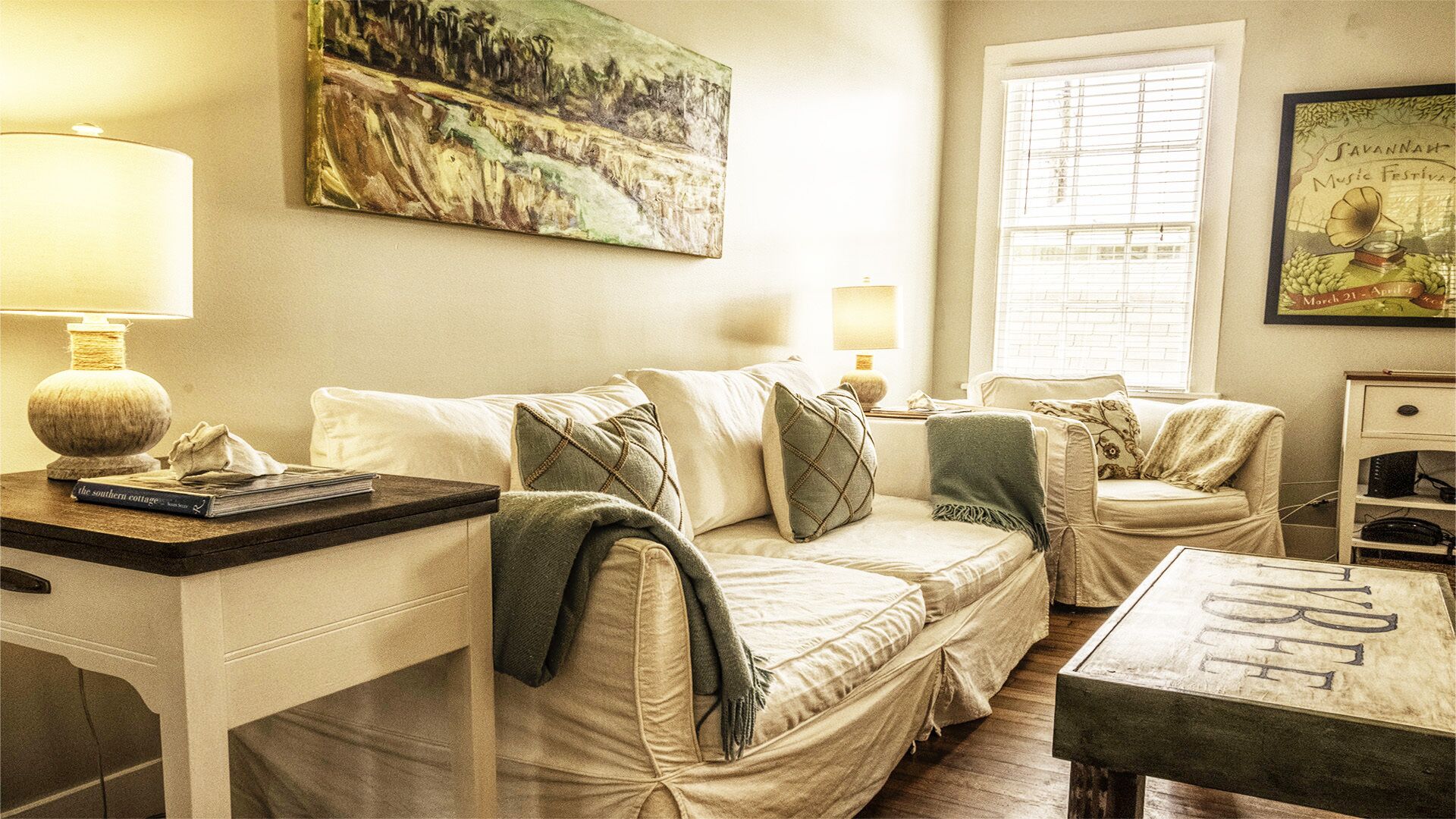 A cozy living room with a sofa, a coffee table, and a painting on the wall.