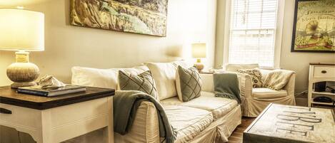 A cozy living room with a sofa, a coffee table, and a painting on the wall.