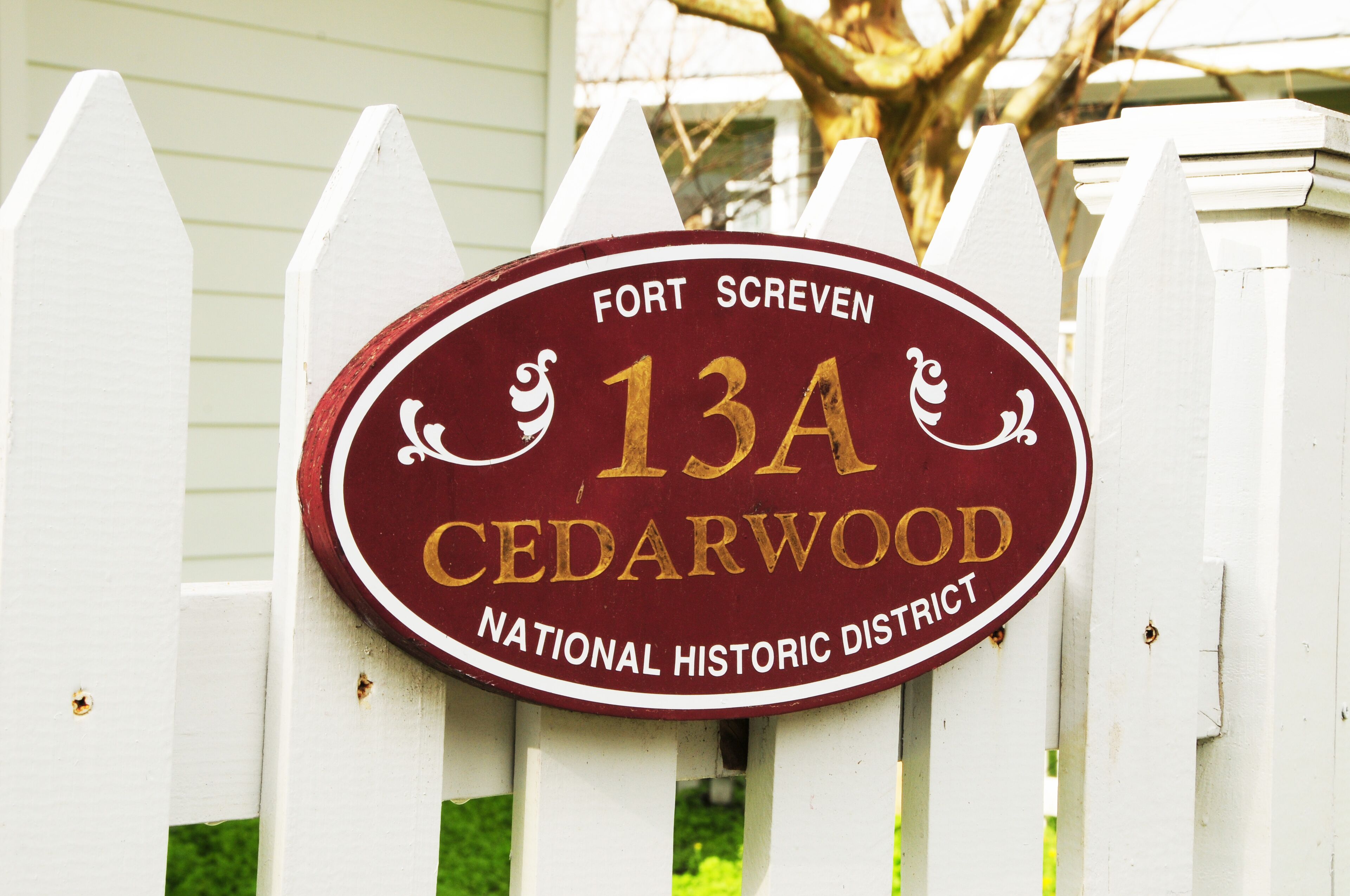 A white picket fence with a sign that reads 'Fort Screven 13A Cedarwood National Historic District.'