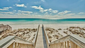 A wooden boardwalk leading to a beach with clear skies and calm waters.