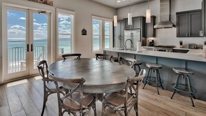 A modern kitchen with a large island, bar stools, and a view of the ocean.