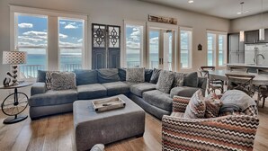 A spacious living room with a large sectional sofa, a patterned armchair, and a dining area with a table and chairs.