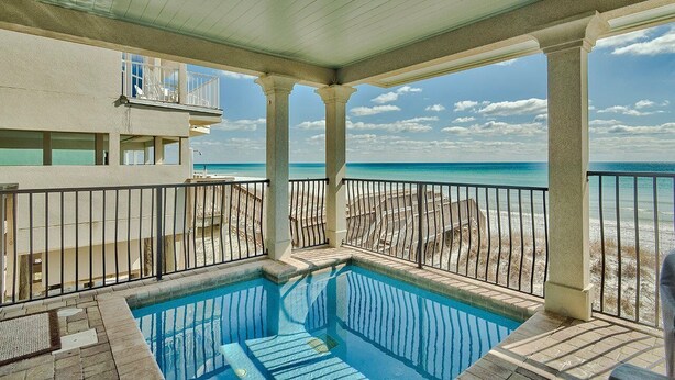 A pool area with a view of the beach and ocean.
