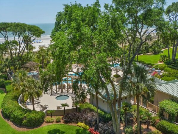 A resort with a pool, lounge chairs, and a view of the beach.