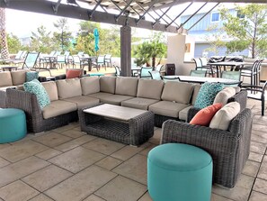 Ein Sitzbereich im Freien mit Korbmöbeln, einem Couchtisch und einer überdachten Terrasse.