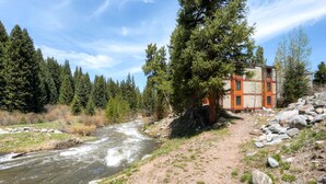 A riverside cabin with a view of a flowing river, surrounded by dense forest. - Enchanting Mountain Haven: Ski, Explore & Relax with Unrivaled VIEWS! (Breckenridge)