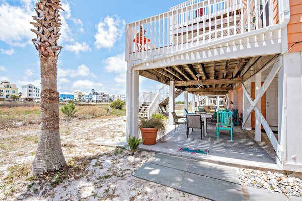 A covered outdoor area with a wooden deck, a small table, chairs, and a potted plant.