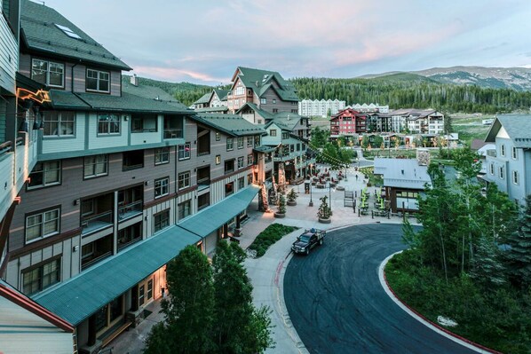 A multi-story hotel with a central courtyard, surrounded by buildings with balconies and a mountain backdrop.