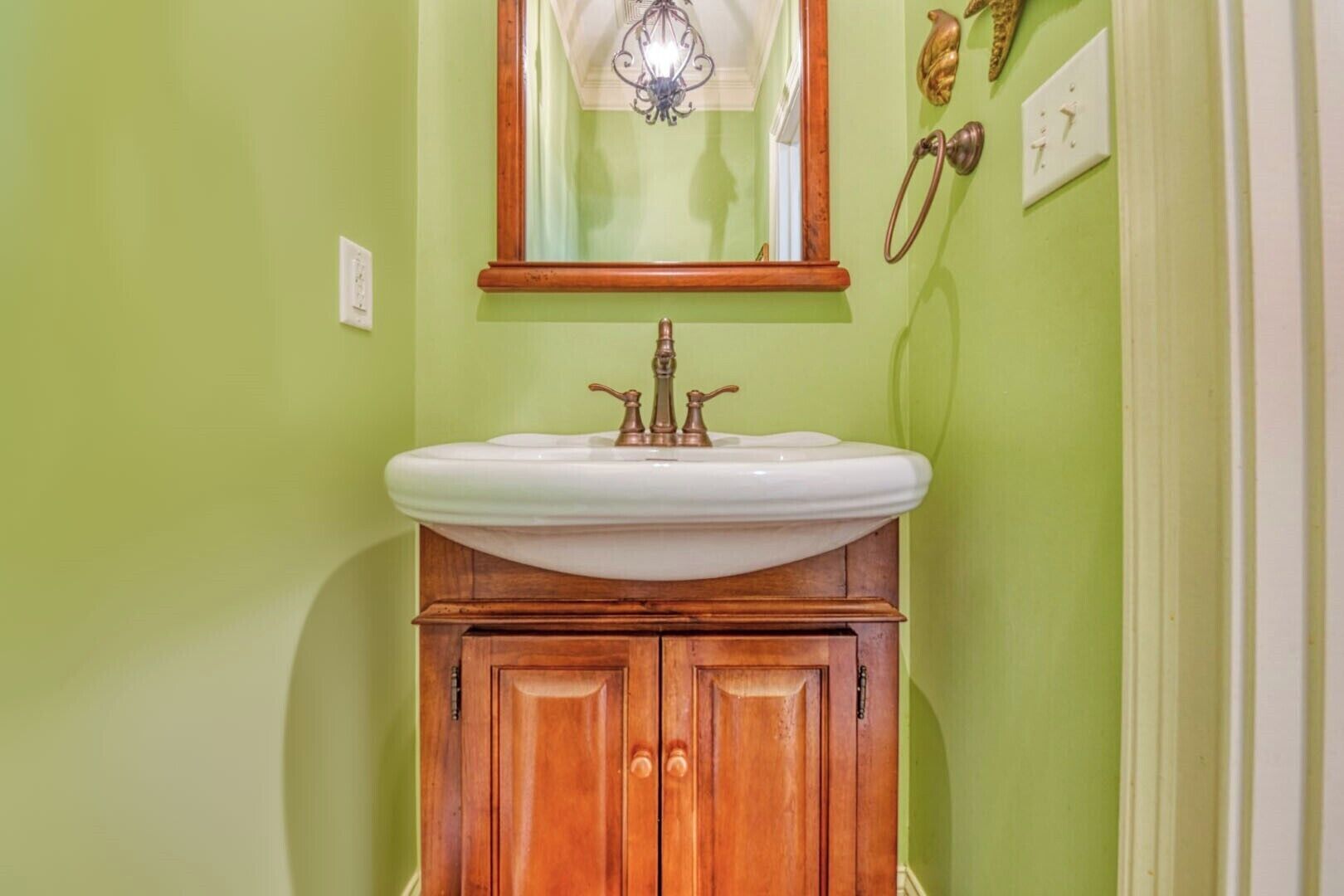 A bathroom with a white sink, wooden vanity, and a mirror above it.