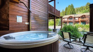 Un jacuzzi en una cabaña de madera con vistas a un albergue y árboles.