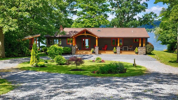 Un chalet avec une façade en pierre, une véranda et une vue sur un lac.