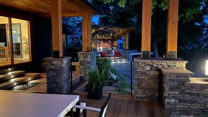 Un espace extérieur aménagé en terrasse, avec des murs en pierre, une plateforme en bois et un coin salon.