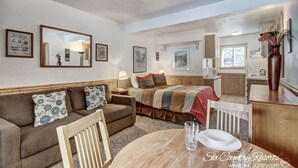 A cozy living room with a sofa, a dining table, and a kitchen area in the background. - Affordable Condo in Downtown Breck. Spacious Shared Lobby w/ Hot Tubs | PM3B (Breckenridge)