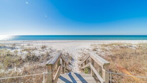 A wooden boardwalk leading to a beach with clear skies.