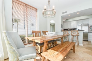 A dining area with a wooden table, chairs, and a bench. There is a chandelier above the table.