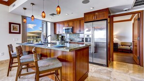 Een moderne keuken met houten kastjes, roestvrijstalen apparatuur en een groot eiland met barkrukken.
