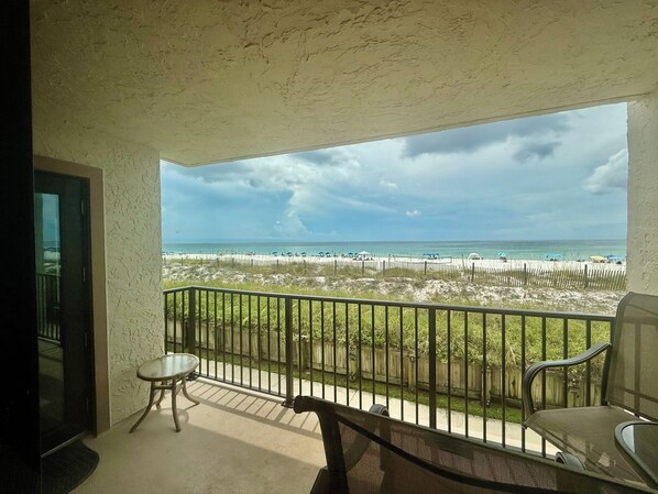 A balcony with a view of the beach and ocean.