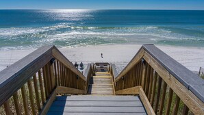 A wooden boardwalk leading to a beach with a clear view of the ocean.