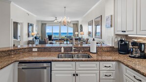 A modern kitchen with granite countertops, stainless steel appliances, and white cabinetry.