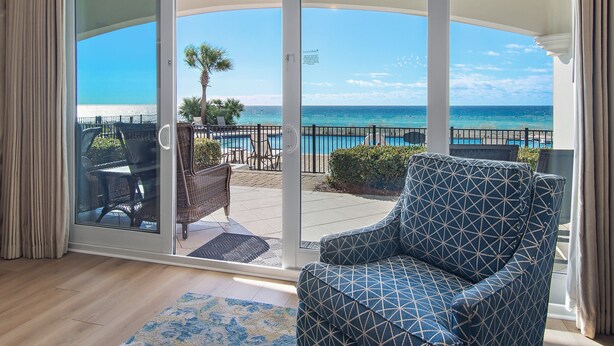 A room with a large sliding glass door leading to a balcony with a view of the ocean.