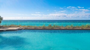 A clear view of a swimming pool with a 3ft depth marker, surrounded by a concrete deck and a row of palm trees.