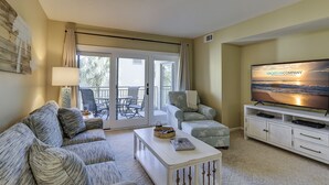 A living room with a sofa, armchairs, a coffee table, a TV, and a balcony with outdoor furniture. - 238 Shorewood- 2nd Floor Landscape View steps to the beach. (Hilton Head Island)
