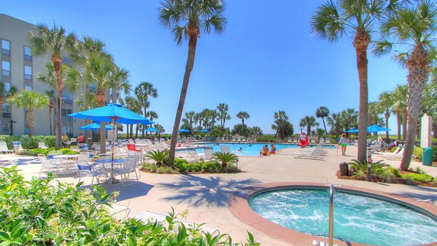 A resort pool area with lounge chairs and umbrellas, surrounded by palm trees. - 238 Shorewood- 2nd Floor Landscape View steps to the beach. (Hilton Head Island)