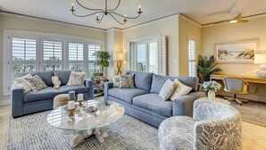 A spacious living room with two sofas, a glass coffee table, and a chandelier. - 3 bedroom/3 bathroom 2nd floor oceanfront condo with lots of amenities (Hilton Head Island)