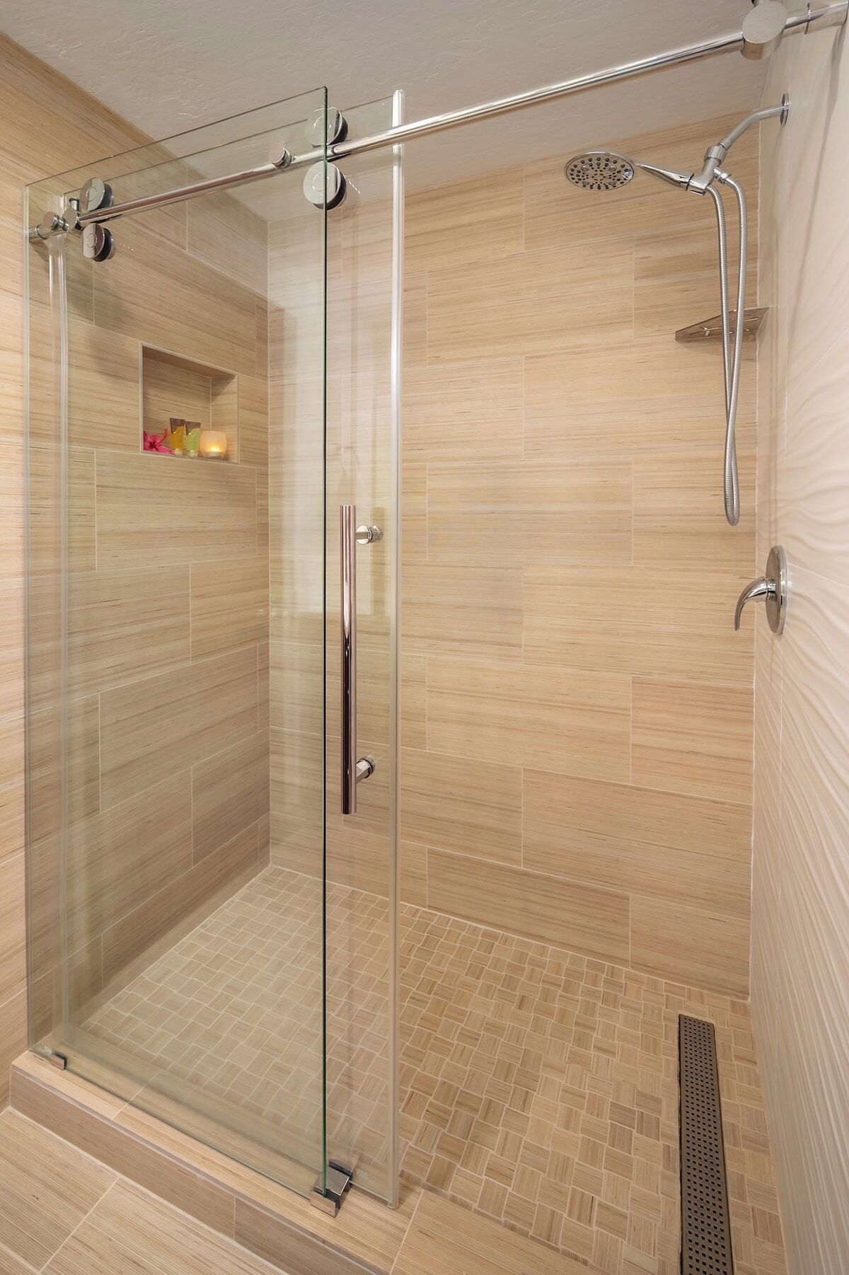 A glass-enclosed walk-in shower with a showerhead and a handheld shower attachment.