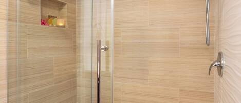 A glass-enclosed walk-in shower with a showerhead and a handheld shower attachment.