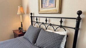 Un lit avec une couvre-lit matelassé, deux oreillers, une table de chevet avec une lampe et un tableau encadré accroché au mur.