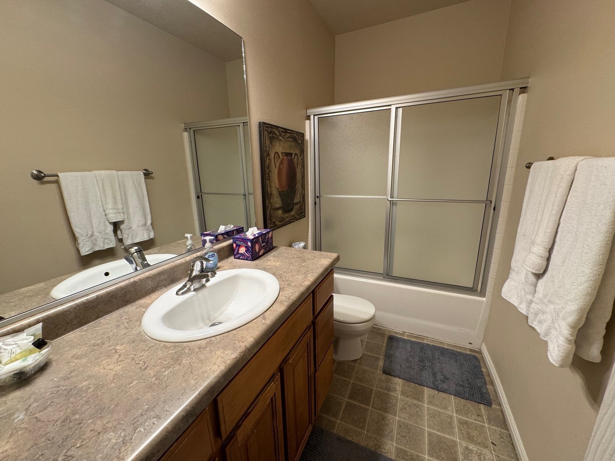 A bathroom with a sink, mirror, toilet, and shower.