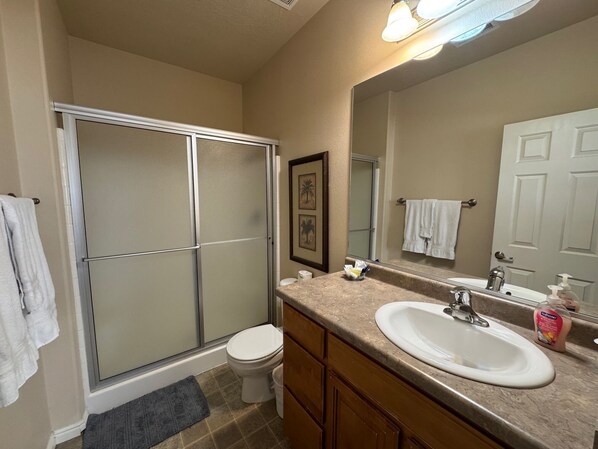 A bathroom with a shower, toilet, sink, and a large mirror. - Par-Tee House by Mesquite Vacation Rentals with Community Amenities and $510 in free daily activities (Mesquite)