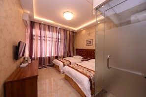 Une chambre d’hôtel avec deux lits, un bureau, une télévision et un espace douche.