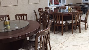 Uma área de refeições com uma mesa redonda e cadeiras, uma janela com vista e um chão ladrilhado.