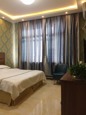 Une chambre d’hôtel avec un lit, un bureau, une chaise et une grande fenêtre avec des rideaux.