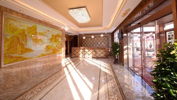 Um hall amplo com um mural grande, um candelabro e uma área de recepção.