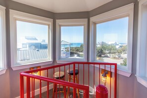 A corner room with three large windows offering views of the sea and surrounding buildings.