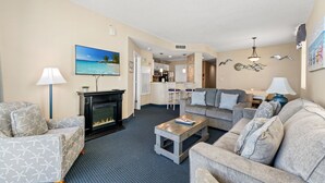 Ein Wohnzimmer mit Kamin, Sofas, einem Couchtisch und einem Gemälde, das eine Strandansicht zeigt.