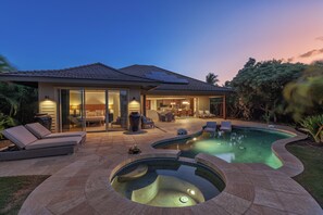 Una casa moderna con piscina, zona de estar exterior y un patio bien iluminado.