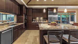 A modern kitchen with dark wood cabinets, granite countertops, stainless steel appliances, and pendant lighting. - KaMilo 321 - Beautiful 3 bedroom with private pool! (Kamuela)