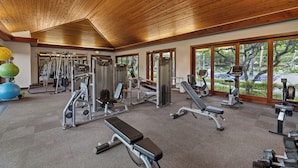 A gym with various exercise equipment, large windows, and a wooden ceiling. - KaMilo 321 - Beautiful 3 bedroom with private pool! (Kamuela)