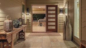 A modern entryway with a wooden bench, a decorative lantern, and a view into a dining area. - KaMilo 321 - Beautiful 3 bedroom with private pool! (Kamuela)