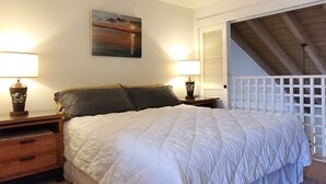 Una camera da letto con un letto grande, due lampade sui comodini, un quadro appeso al muro e una ventola a soffitto in legno.