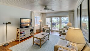 A spacious living room with a television, sofa, and a ceiling fan.