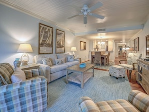 A cozy living room with a sofa, armchairs, a coffee table, and a dining area with a chandelier. - 457 Captains Walk- Just walk out your living area to the beach. (Hilton Head Island)