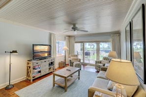 A spacious living room with a television, sofa, and a ceiling fan. - 457 Captains Walk- Just walk out your living area to the beach. (Hilton Head Island)