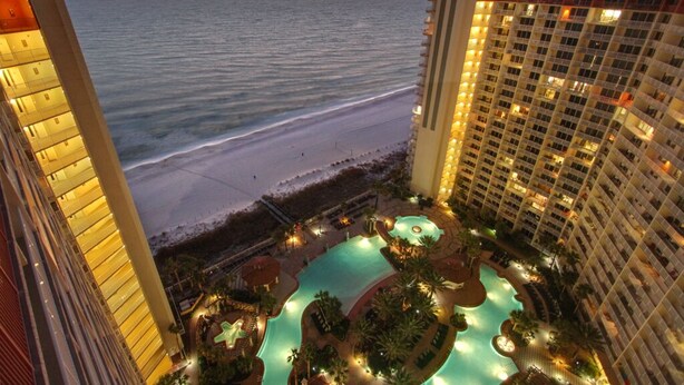Un hotel con zona de piscina, vista a la playa y edificios altos.