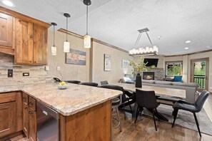 A modern kitchen with granite countertops, wooden cabinets, pendant lighting, and a dining area with a large table and chairs. - Experience the Village at Breckenridge Chateaux 1023: Resort Amenities! (Breckenridge)